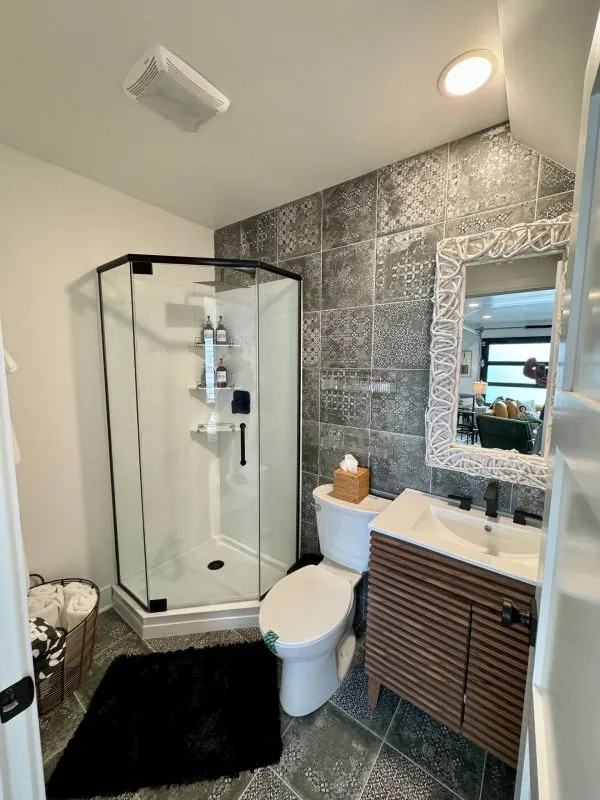 Modern bathroom remodeling with glass shower, decorative tile wall, and wooden vanity in Oswego, Illinois.