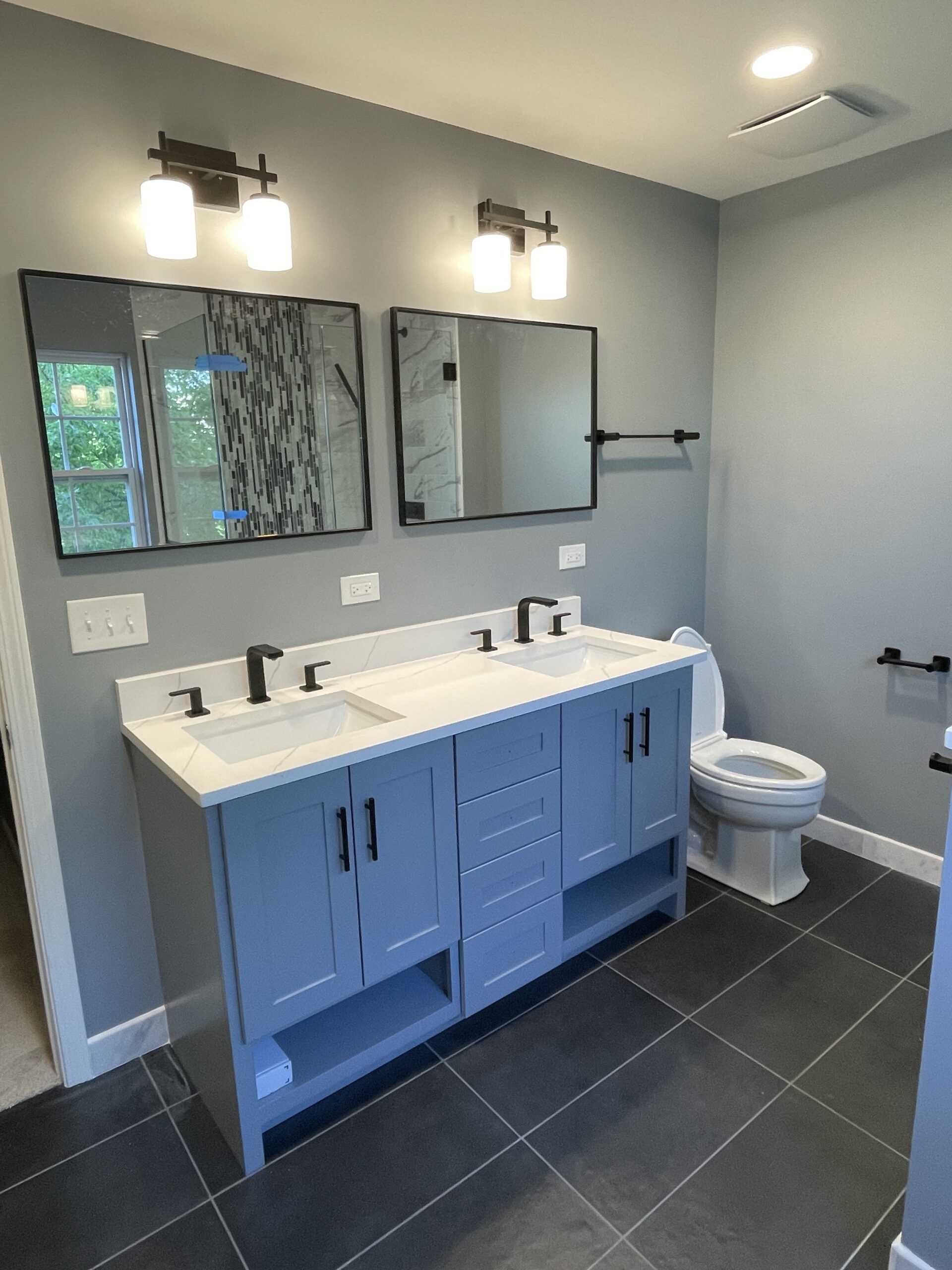 A double vanity with white countertops. All black hardware.