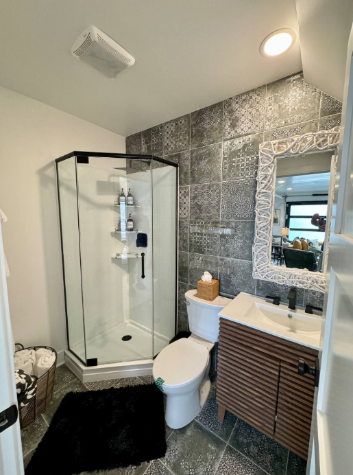 Stylish bathroom with patterned tile, abstract mirror, and matte black fixtures