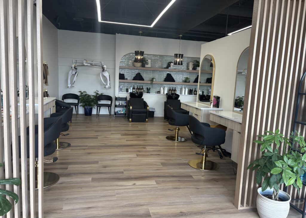 Boho-inspired hair salon featuring neutral color palette, wood flooring, and blue-green decorative accents