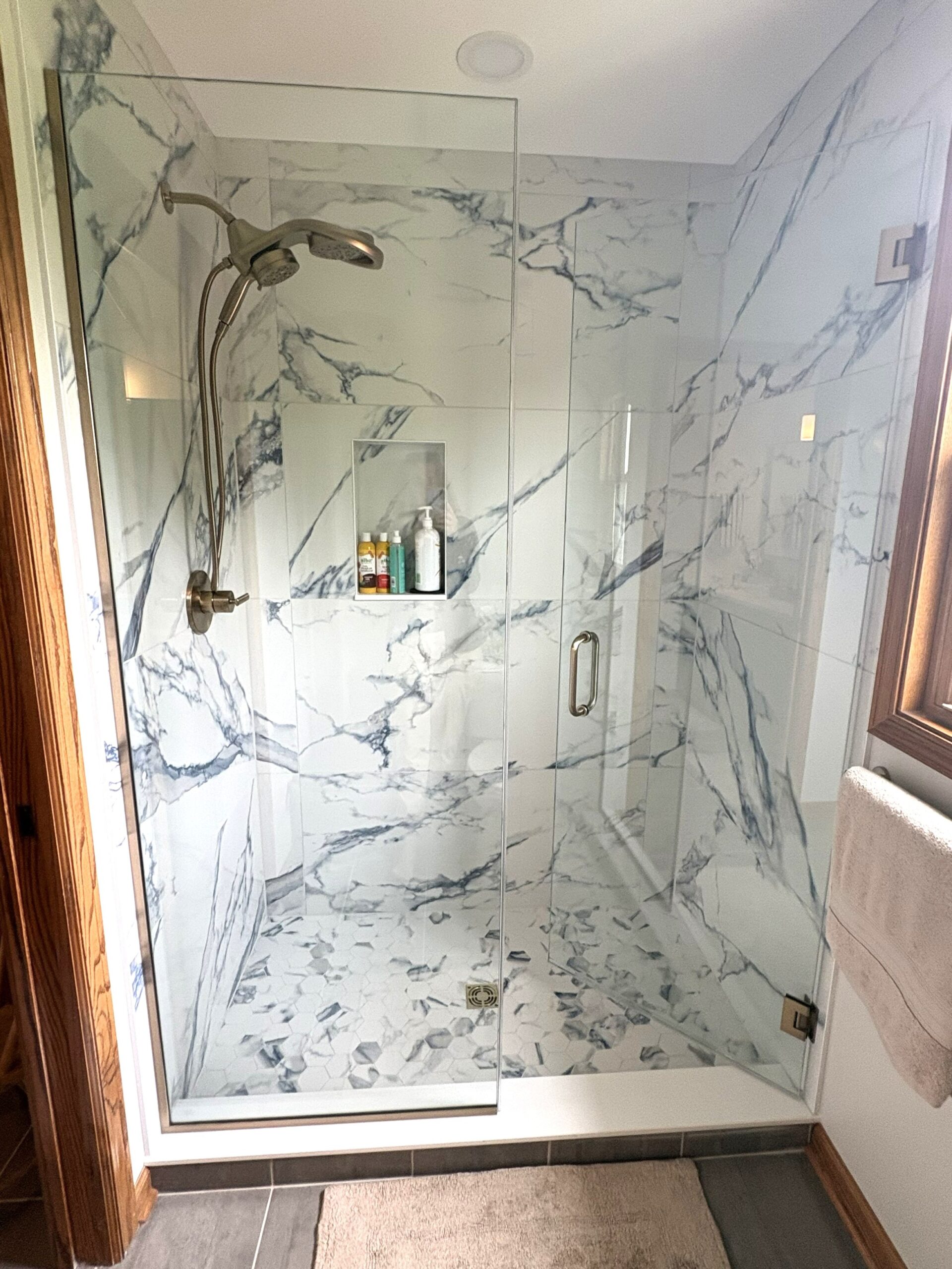 Walk-in shower remodel in Oswego, IL featuring white marble tile and a frameless glass shower enclosure