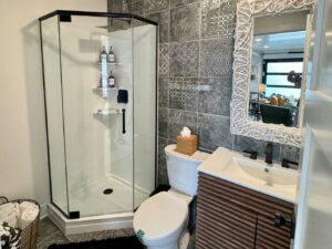 Custom bathroom remodel with patterned tile, abstract wall mirror, and matte black plumbing fixtures
